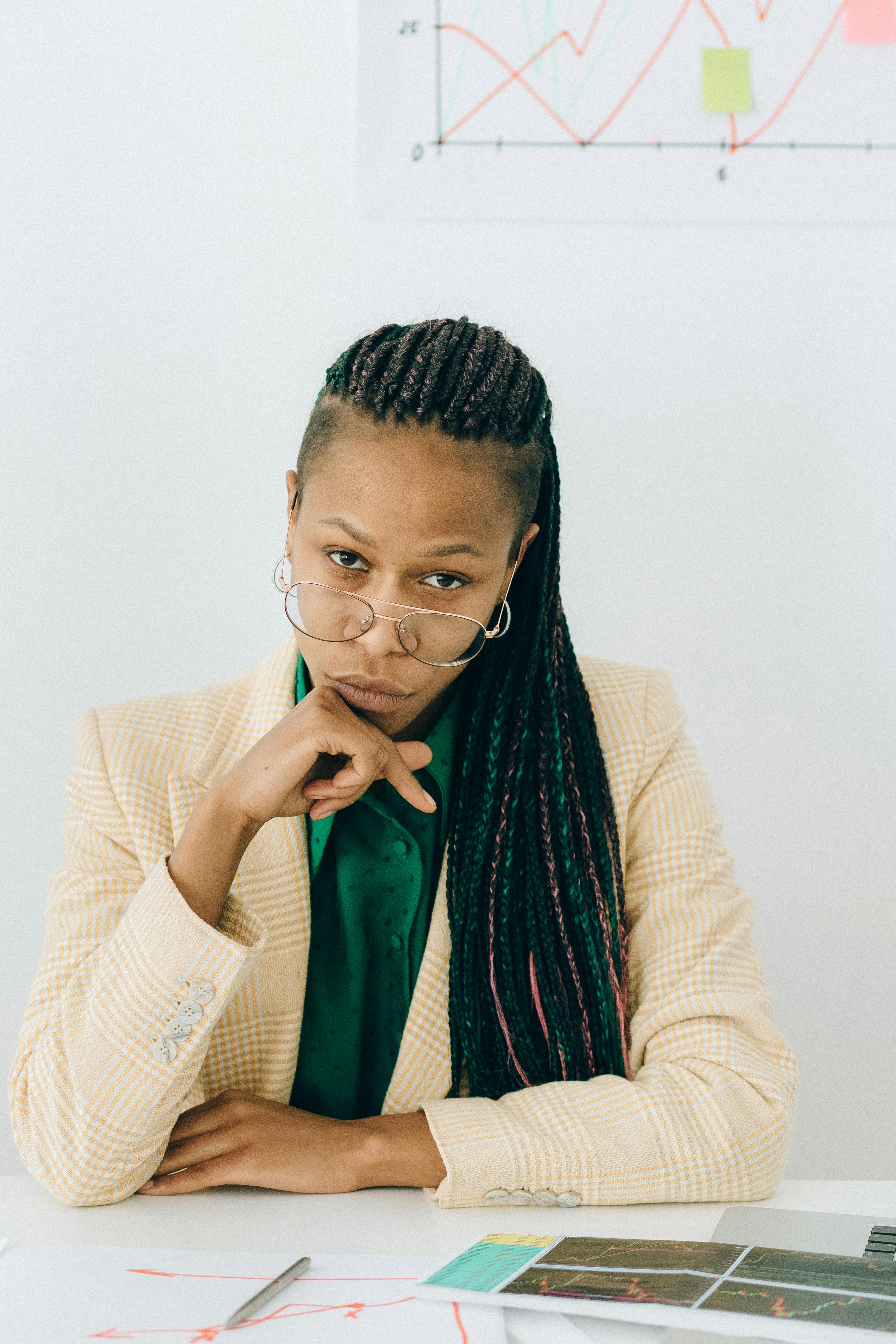 woman in a beige coat wearing eyeglasses while looking at the camera