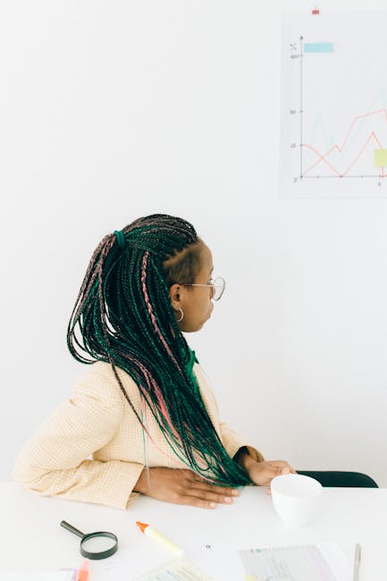 Woman in Beige Coat Looking at the Graph on the Wall while Holding the White Cup