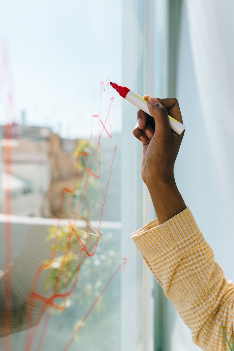 A Person Writing On A Glass Panel Using A Whiteboard Marker