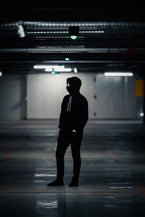 Man in Black Hoodie Standing in the Covered Car Park