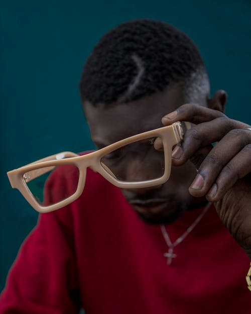 Man in Red Shirt Holding Brown Framed Eyeglasses