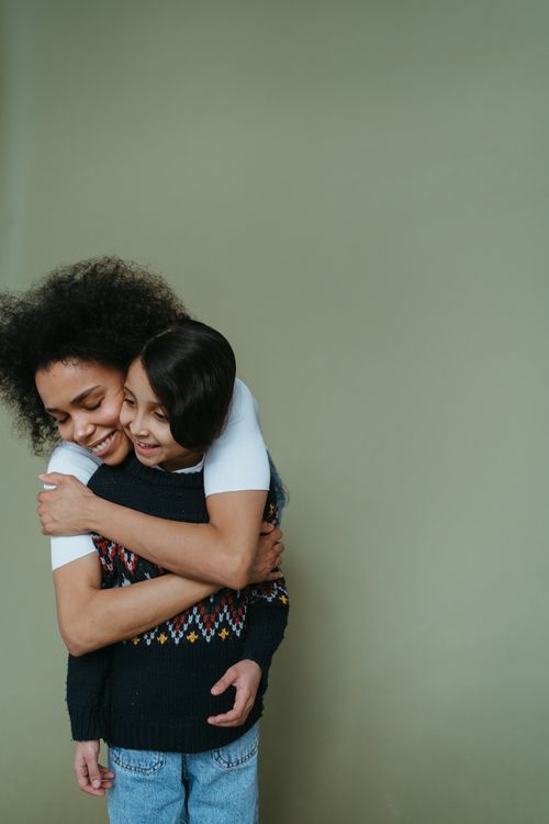 Free Two friends embrace joyfully against a minimalist green background. Stock Photo