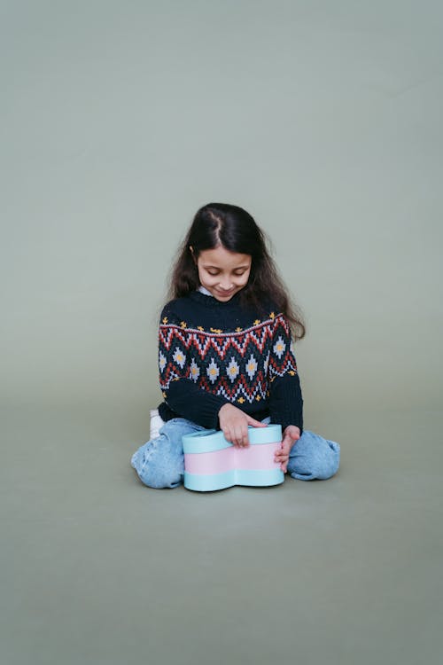 A Girl Knitted Sweater Sitting on the Floor while Looking Down