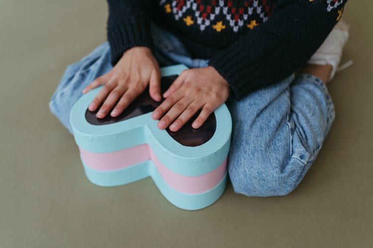 A Child Touching A Heart Container