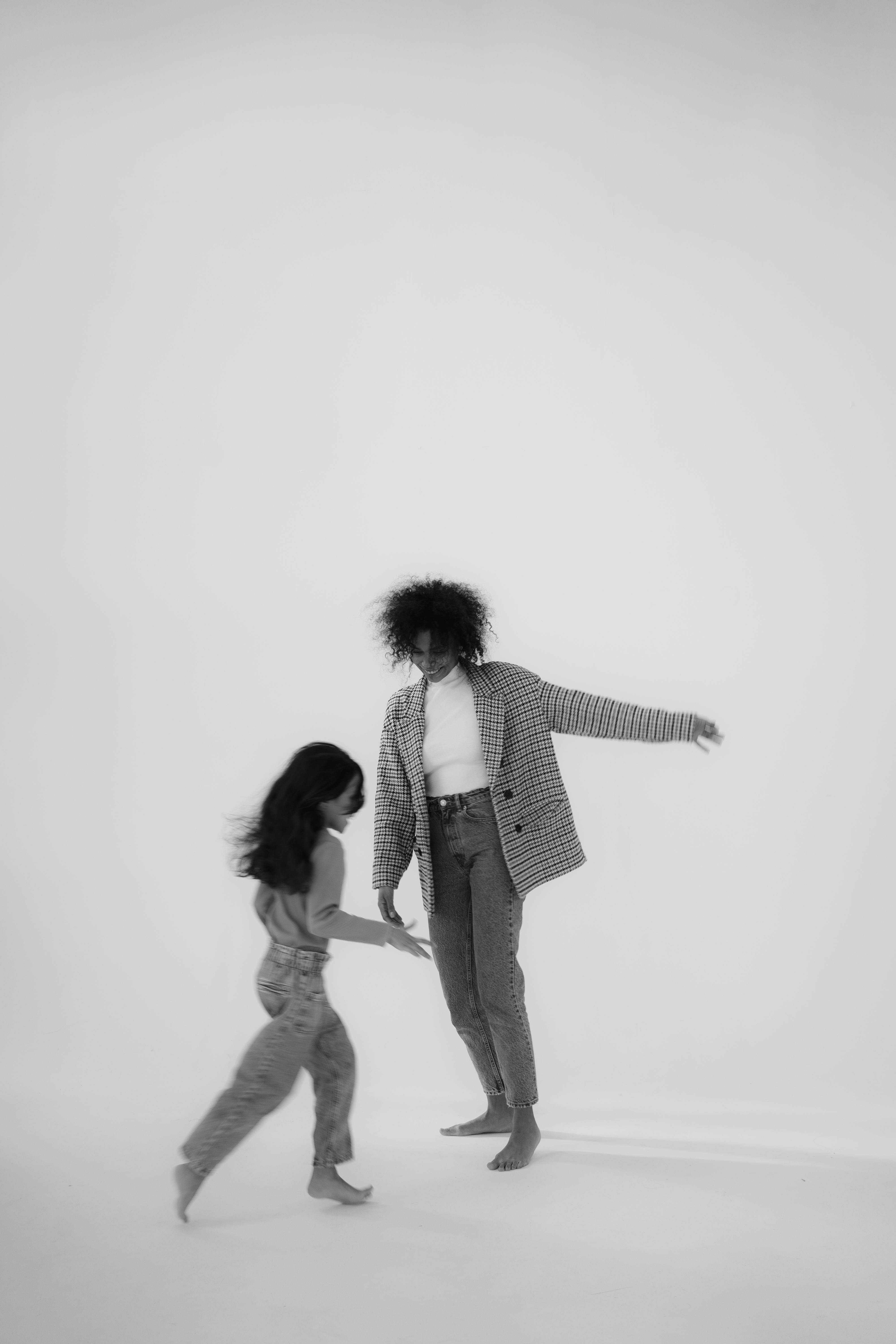 A black and white image of a mother and child dancing playfully together in a studio.