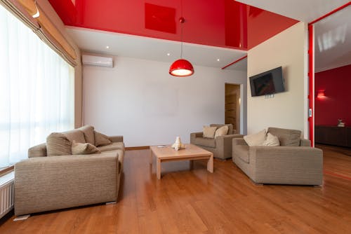 Interior of spacious living room with comfortable sofa and armchairs placed near table in contemporary flat