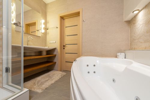 Free Interior of modern bathroom with shower near bath and sink on cabinet under mirror next to door Stock Photo