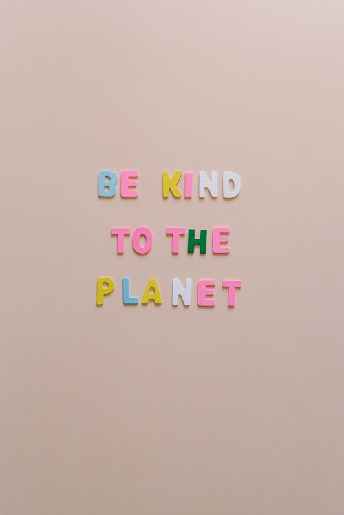 Free Colorful magnetic letters spelling 'Be Kind to the Planet' on a beige background. Stock Photo