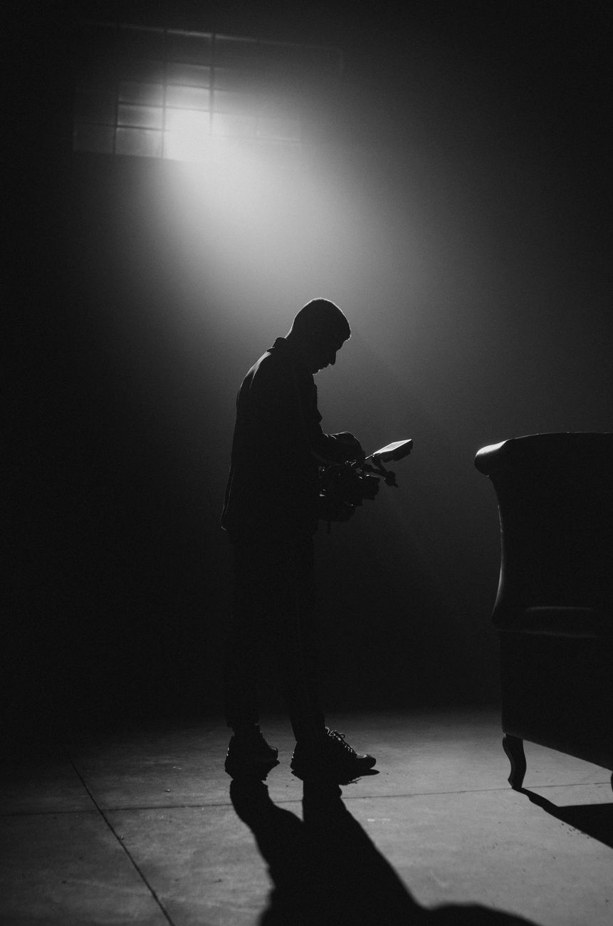 Indrukwekkende silhouet van een cameraman op een filmset die schaduwen cast in een zwart-wit scène.