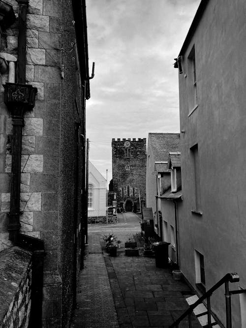 Black and white narrow pedestrian street between old residential buildings in historic town district