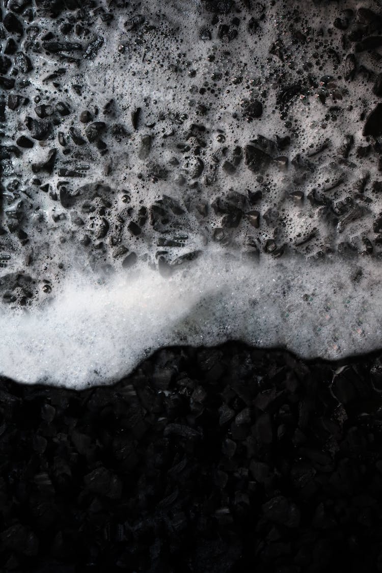 Water Splashing On Black Stones On Beach