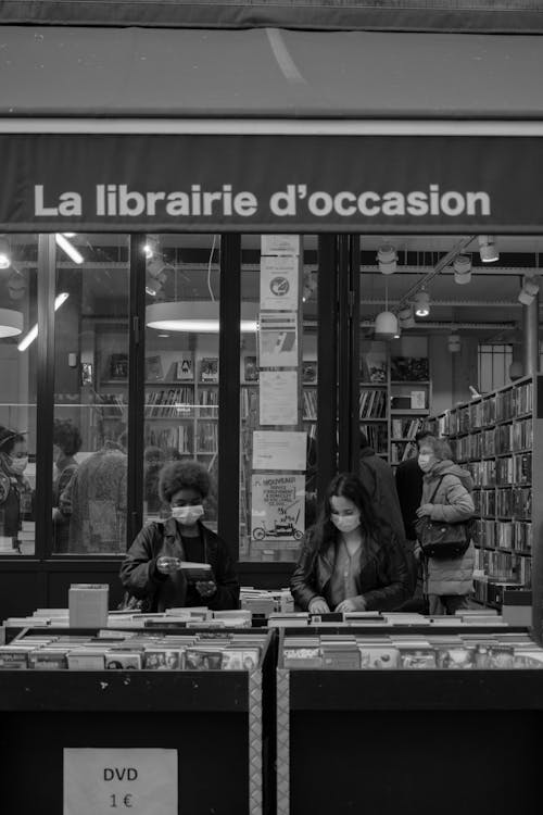 Grayscale Photo of Women Searching for Books in the Bookstore
