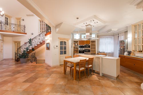 Interior of spacious apartment with open kitchen with chairs and counter near cupboards next to stairway