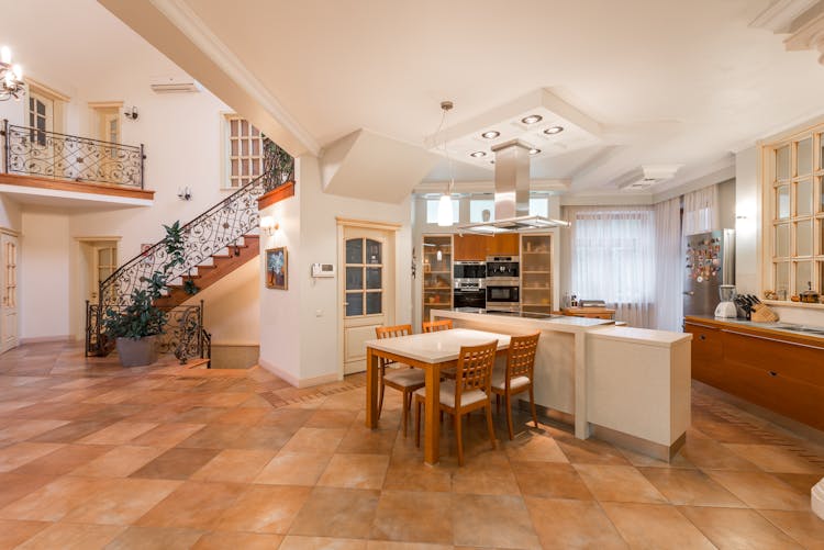 Open Kitchen Interior With Counter And Chairs Near Cabinets