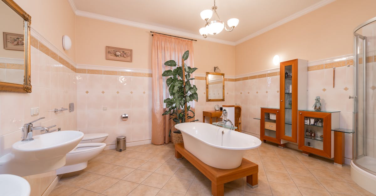Interior design of bathroom with bathtub in centre and shower cabin next to cabinet and table with mirror opposite toilet and bidet near sink and mirror