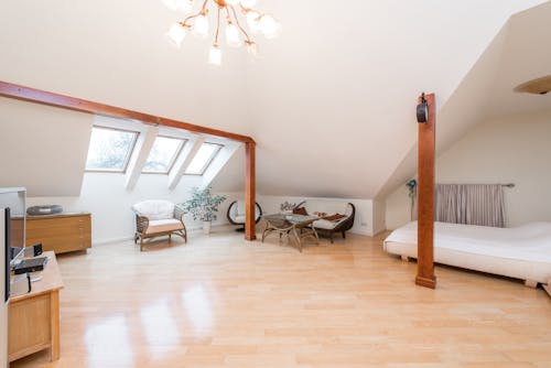 Spacious apartment interior with bed near armchairs and couch next to table and windows near cabinet under chandelier