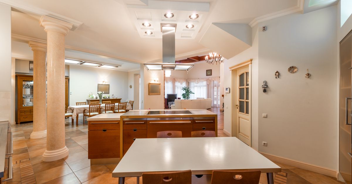 Interior of contemporary spacious dining room with wooden chairs and tables near white columns and shining lamps on ceiling