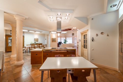 Free Interior of contemporary spacious dining room with wooden chairs and tables near white columns and shining lamps on ceiling Stock Photo