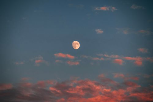 Free A serene image of the moon surrounded by colorful clouds during twilight. Stock Photo