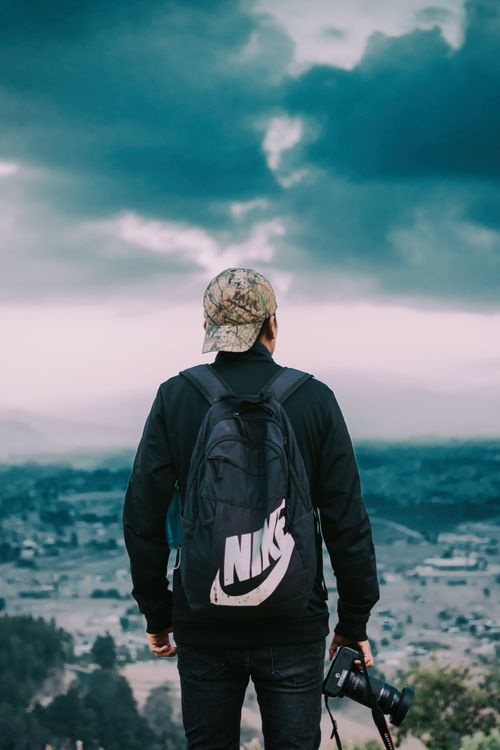 Free A man holding a camera looks at a breathtaking landscape, ready to capture the moment. Stock Photo