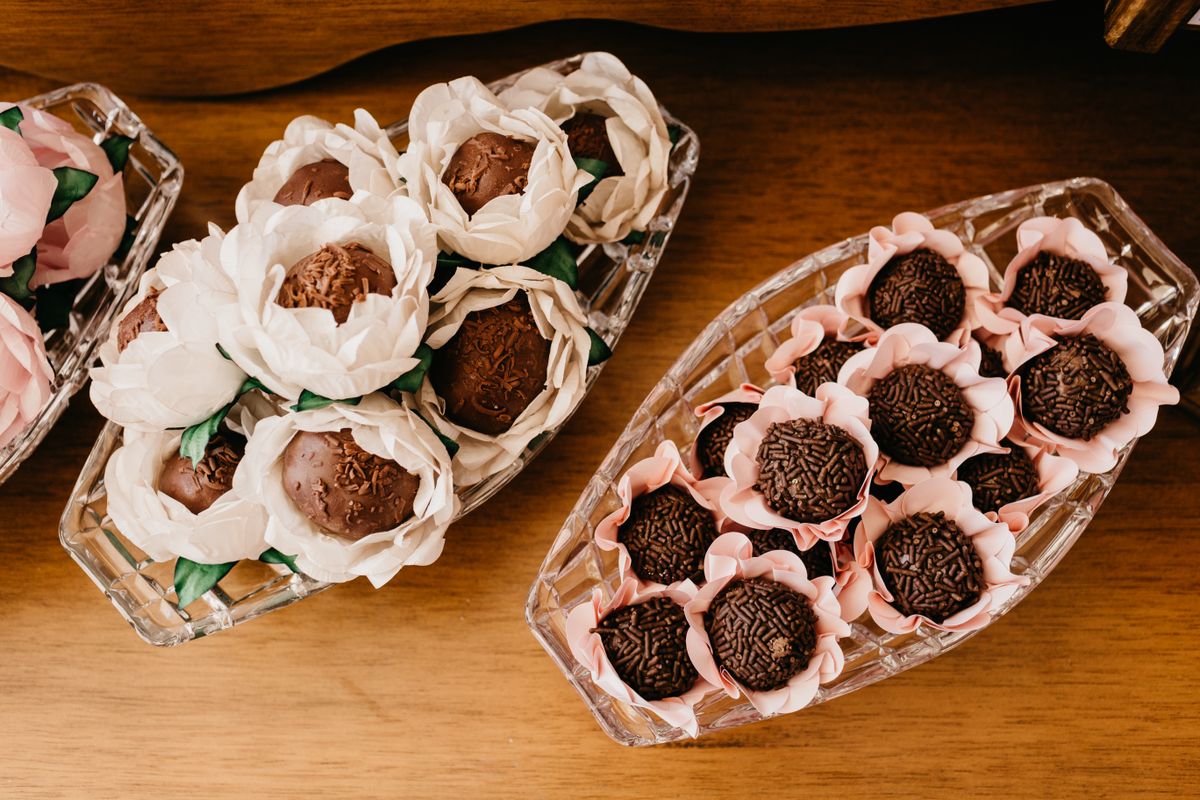 Top view of various tasty sweets of chocolate balls in decorative paper flowers on plates during festive event