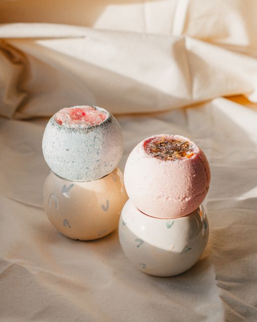 Aromatic pastel bath bombs with bath salt arranged on white cloth in bathroom in sunlight