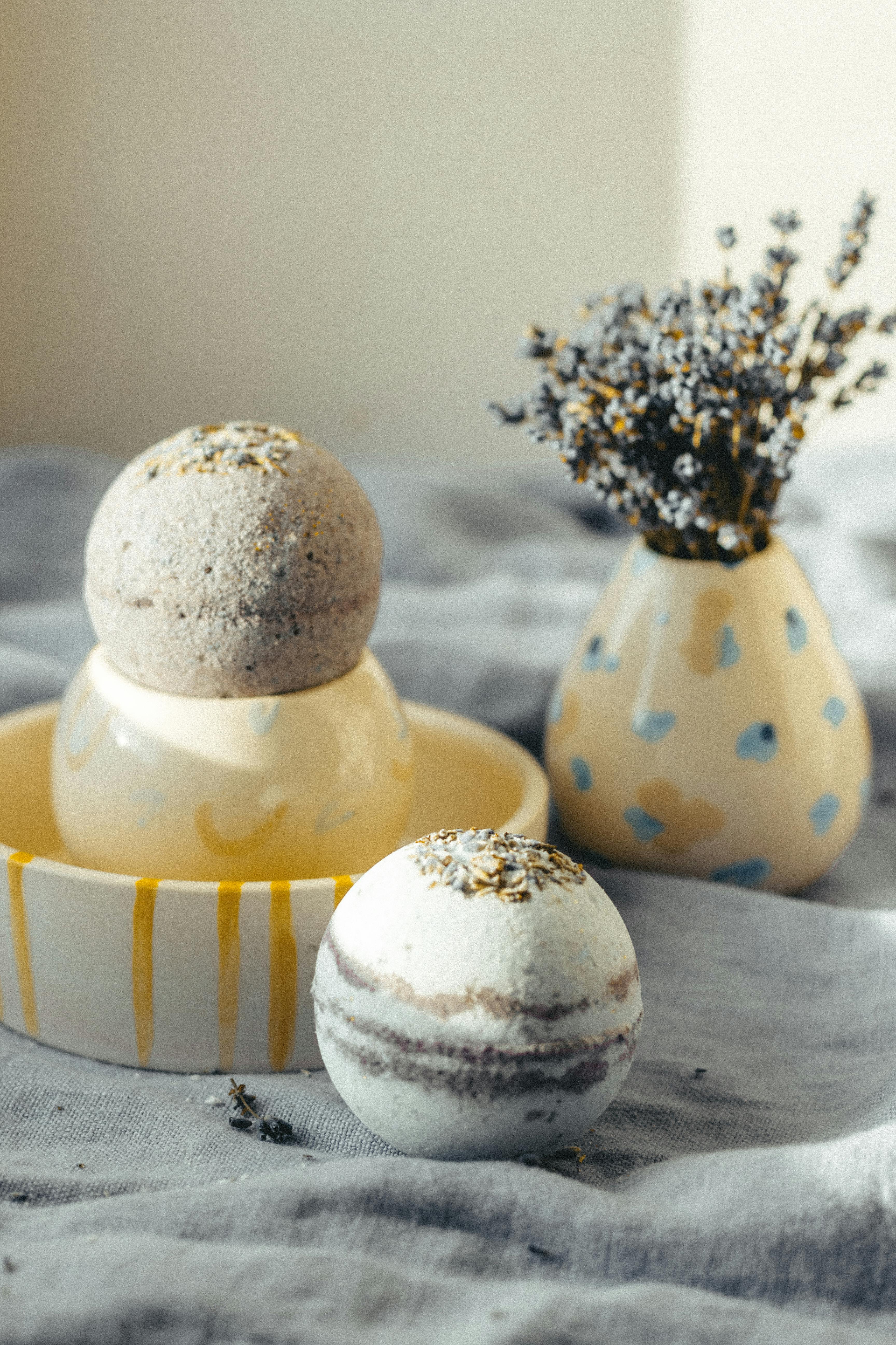 fragrant bath bombs arranged on cloth near vase with flowers