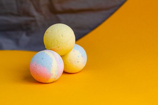 Composition of aromatic colorful bath bombs in shape of balls arranged on yellow table in bathroom