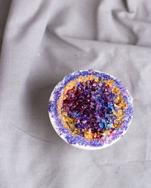Purple bath salt in bowl placed on cloth
