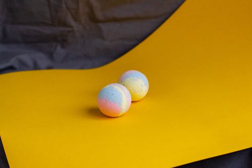 Composition of aromatic bath bombs in pastel colors placed on yellow table in bathroom