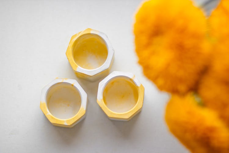 Empty Tealight Holders On White Table Near Yellow Flowers