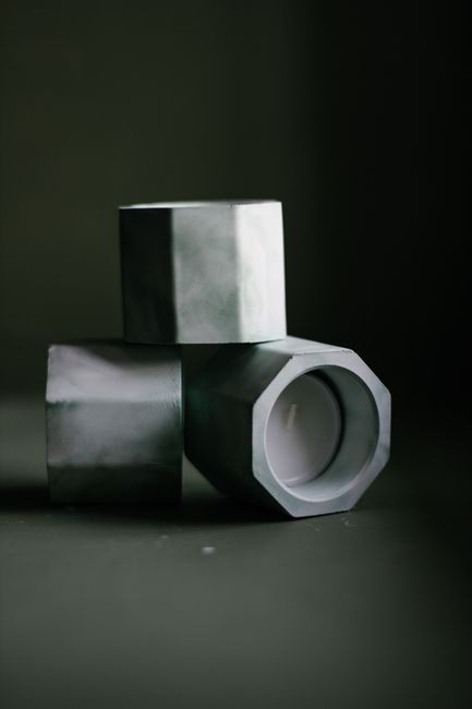 Creative geometric handmade candle holders placed on gray surface in workshop for making plaster decor
