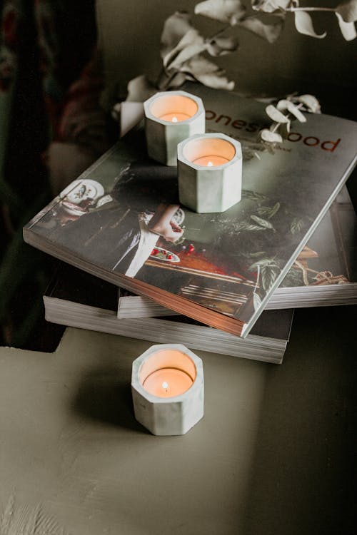 Burning candles in holders on stack of books