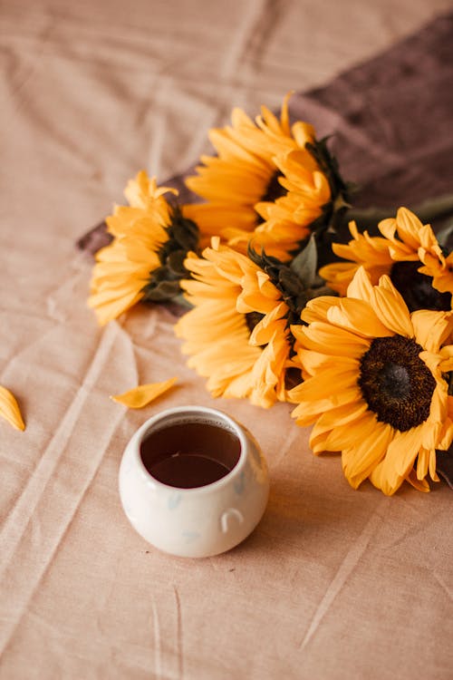 Sunflowers near cup with tea on table with cloth