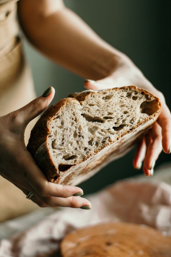 Freshly baked artisan sourdough bread loaf on a rustic wooden table in a cozy kitchen, representing online bread baking courses for beginners