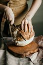 Woman cutting sourdough bread on wooden cutting board