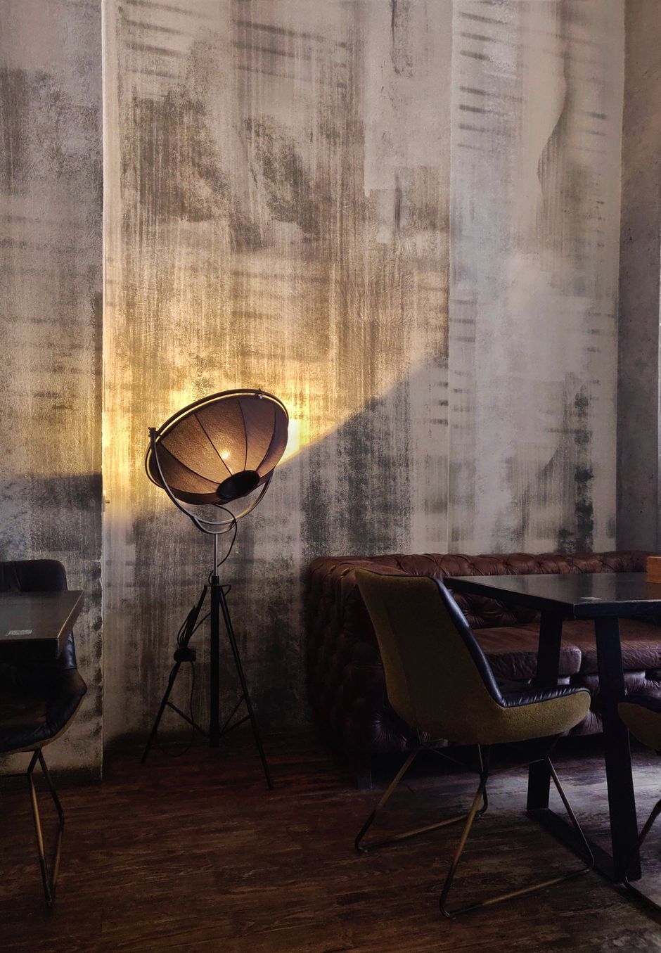 A dimly lit cafe corner with a vintage tripod lamp and rustic decor casting a warm glow.