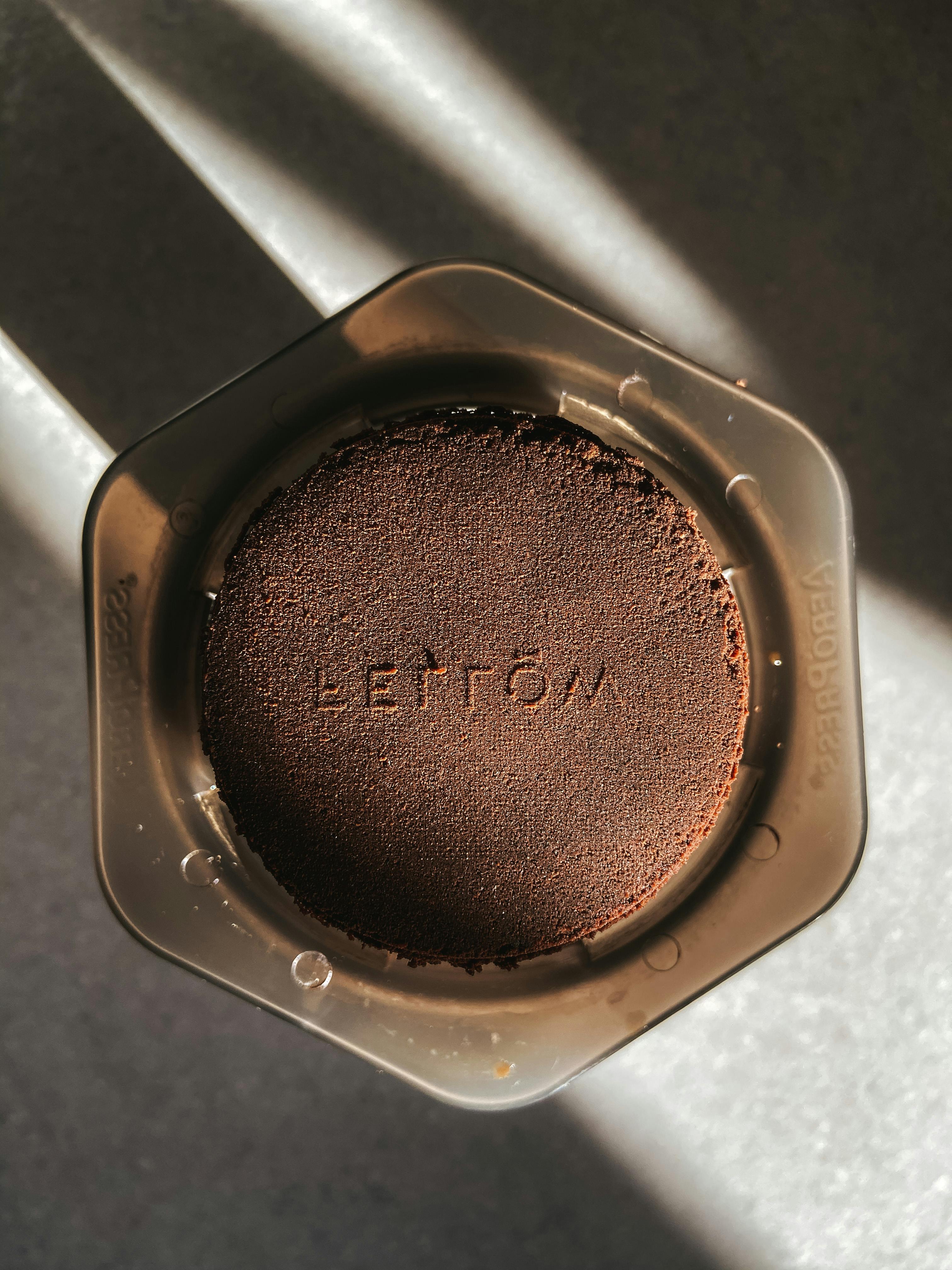 Top view of fragrant ground coffee in plastic aeropress on table in sunlight