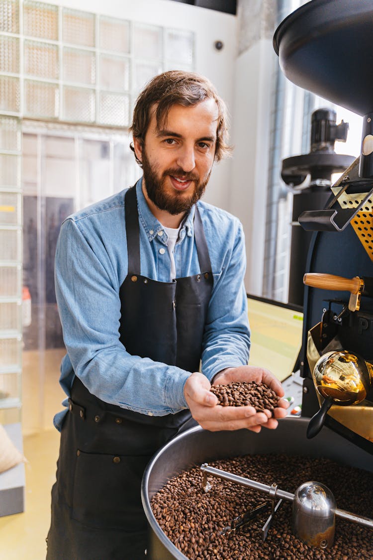 A Man In Blue Long Sleeves Standing Near The Coffee Roaster