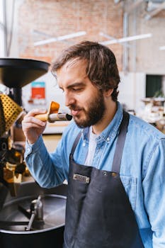 Man sampling and smelling freshly roasted coffee beans in an artisanal coffee shop.