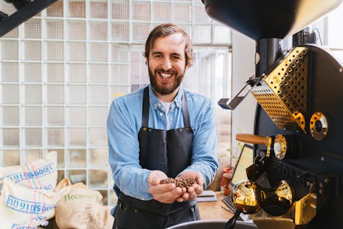 A Bearded Man Smiling while Holding Coffee Beans