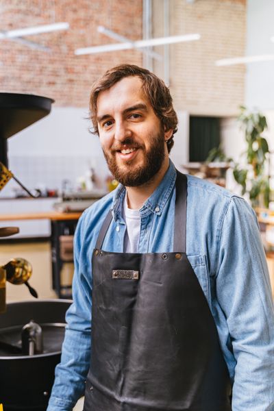 Coffee roaster standing beside his roasting drum — photo by Adventure Studio on Pexels