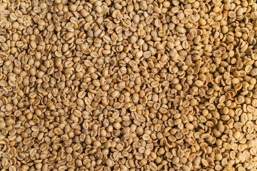 Close-up view of raw unroasted coffee beans showcasing a detailed texture ideal for backgrounds.