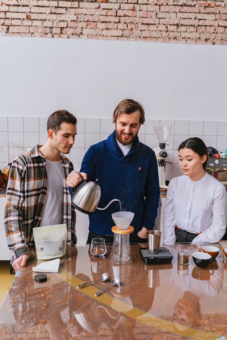 People Making Coffee In Filter At Cafe Kitchen