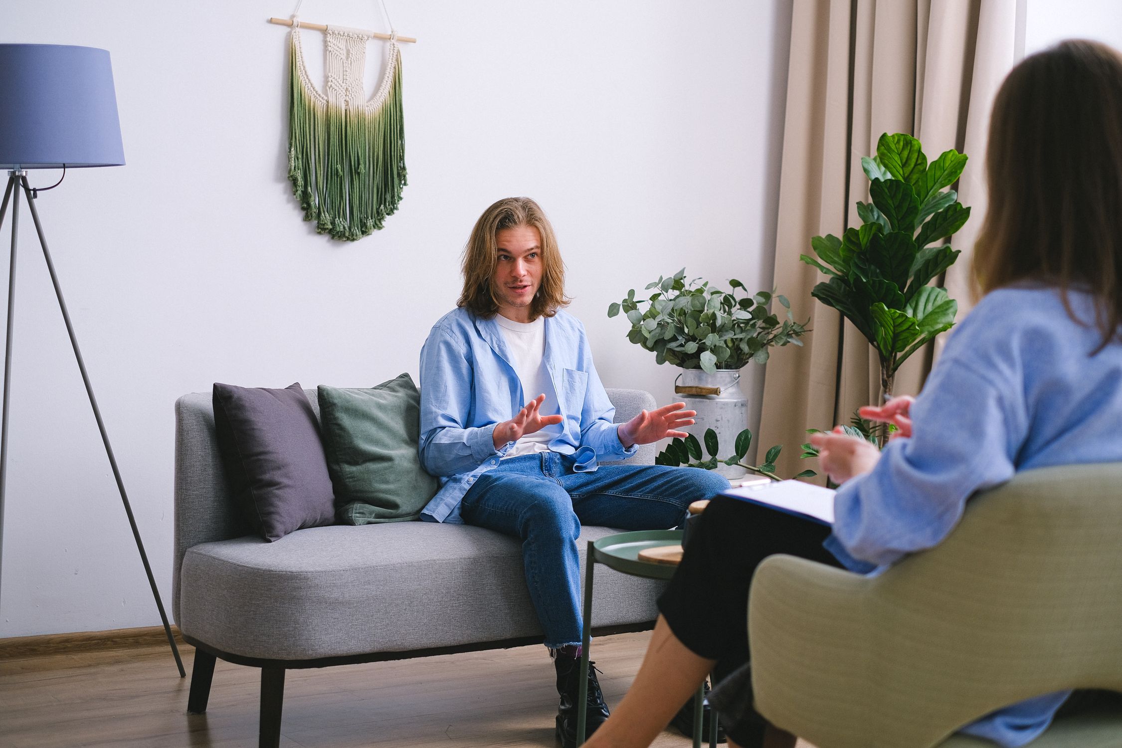 A therapist holding a pen, guiding a client's eyes back and forth in a brightly lit, contemporary room with soft blue accents. The focus is on the calm interaction between the two.
