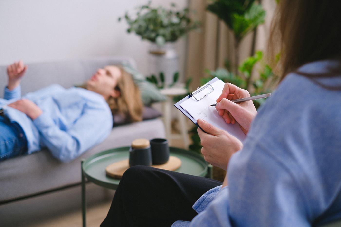 Mental health professional taking notes while speaking with a patient during a consultation