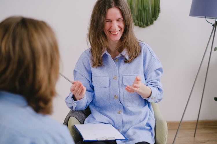 Smiling Woman With Notes Talking At Meeting