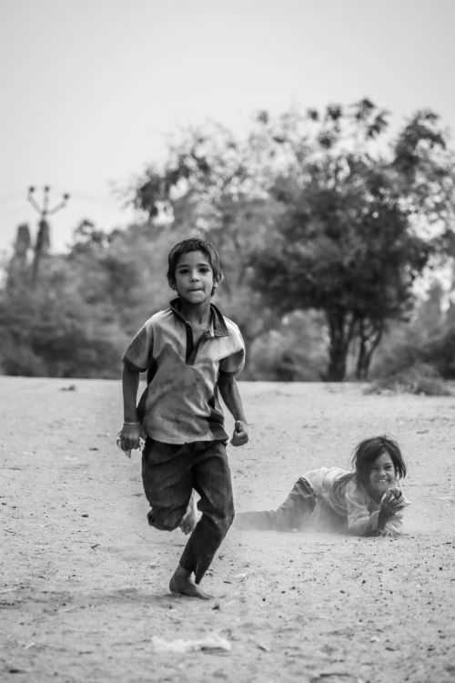 Free Two children enjoying a playful moment outside, captured in classic black and white. Stock Photo