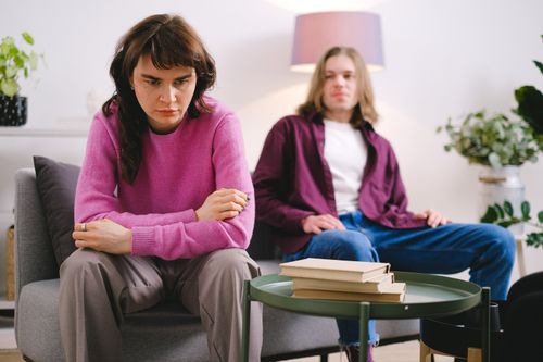 Free A couple sitting on a sofa in a modern living room, deep in thought. Stock Photo