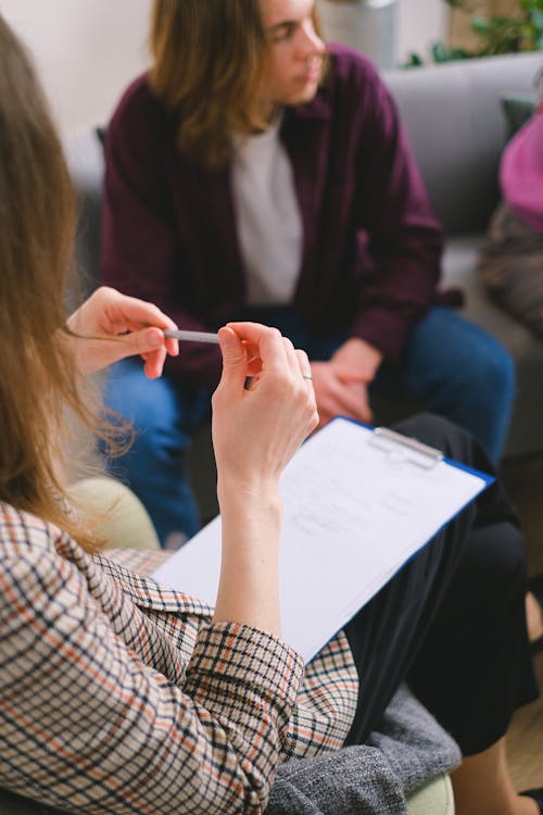 Free A therapist with a clipboard conducting a counseling session with clients. Stock Photo Free A therapist with a clipboard conducting a counseling session with clients. Stock Photo